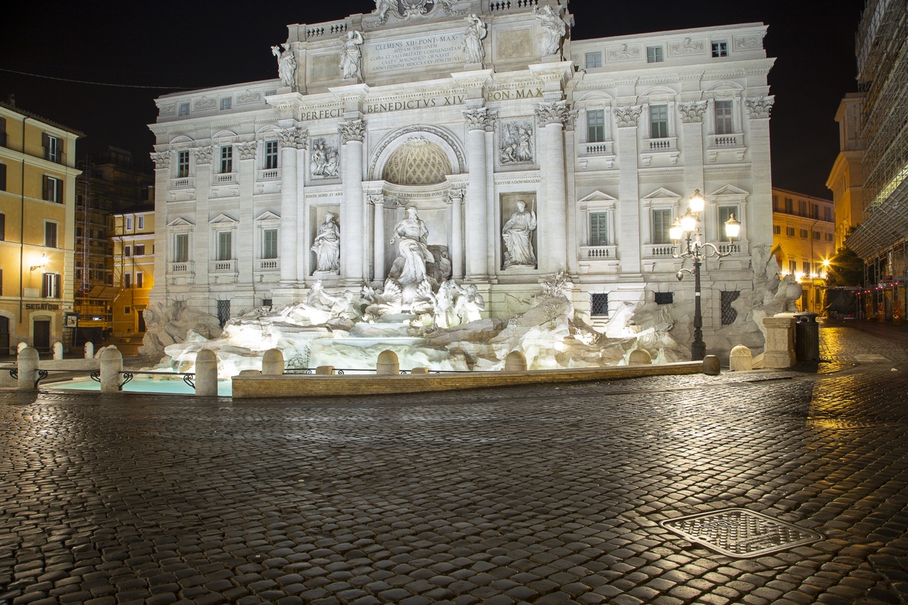 The image shows the illuminated Trevi Fountain at night.