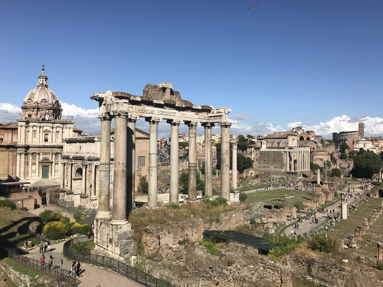 Columns of the Temple of Saturn in the Roman Forum with church domes behind