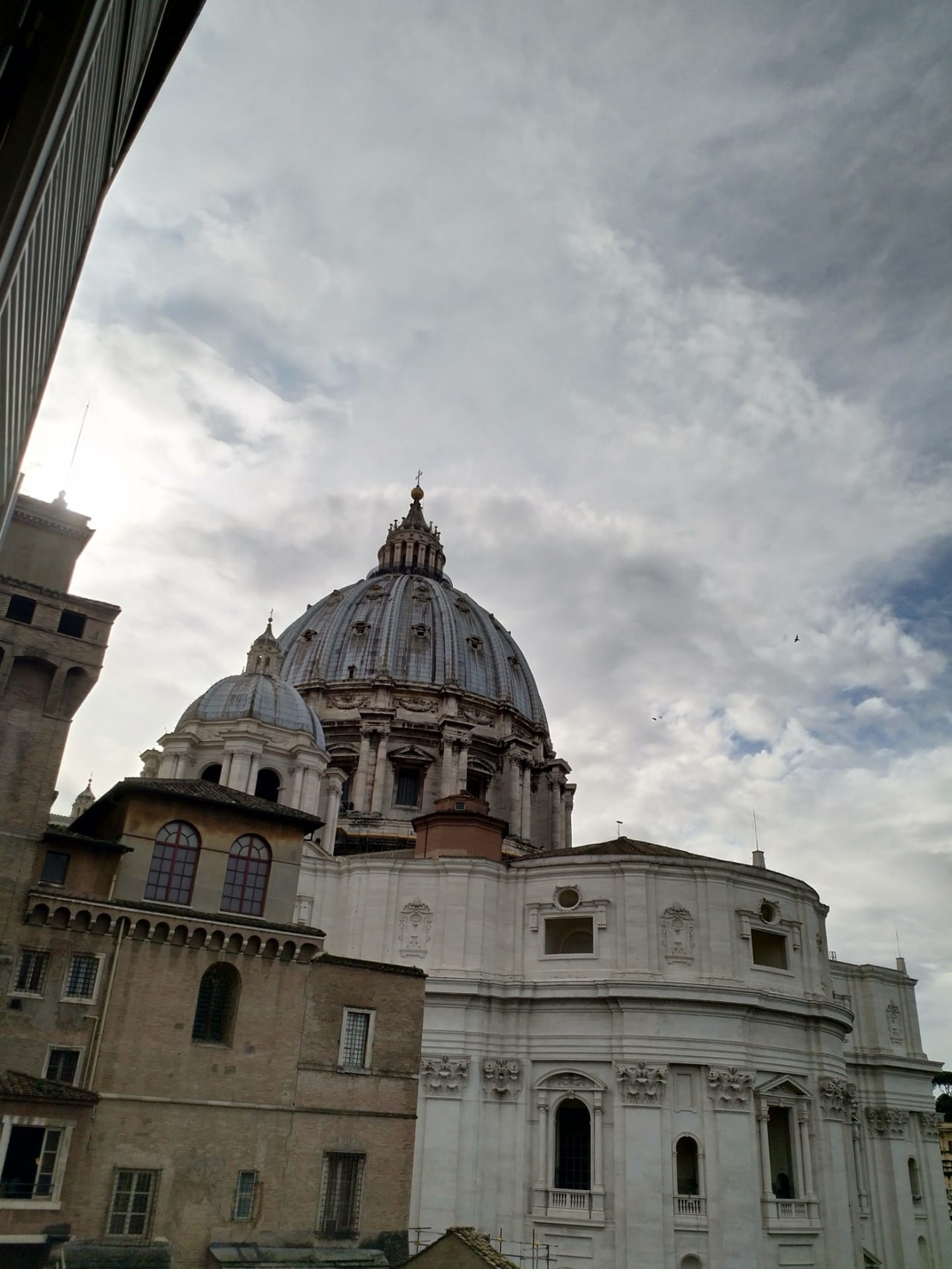 The image shows the dome of St. Peter's Basilica against a cloudy sky.